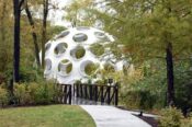 domed art structure that looks like soccer ball off crystal bridge path among trees