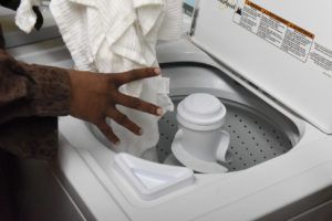 hand placing laundry in washing machine