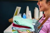 profile of woman smiling as she holds a stack of folded laundry