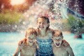 girl and two boys playing in waterfall at waterpark