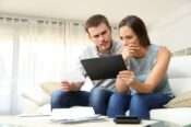 man and woman on sofa looking at paperwork with concerned expressions