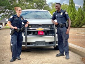 Two officers standing next to a car