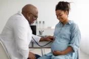 A pregnant woman visits a doctor as he monitors her baby's heartbeat.