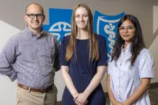 Arkansas Blue Cross and Blue Shield summer interns Dillon Cordel, Lauren LeRoy, and Sayli Naik stand in front of the cross and shield.